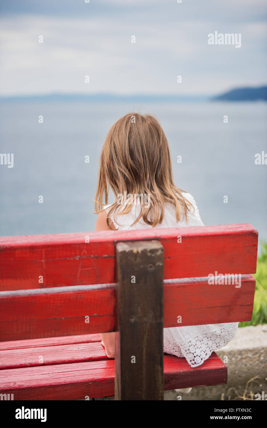 Ragazza seduta su una panchina affacciata sul mare, Grecia Foto Stock