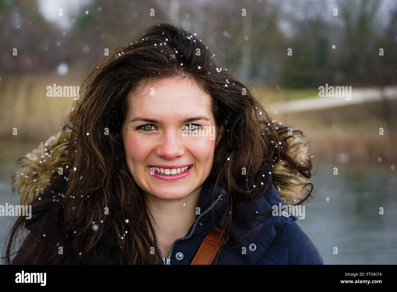 Ritratto di un sorridente giovane donna con i fiocchi di neve nei suoi capelli Foto Stock
