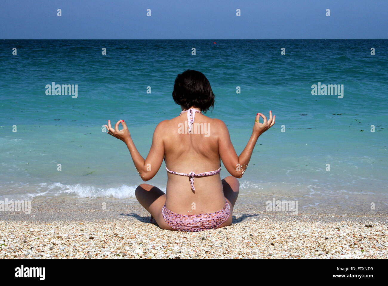 Donna seduta sulla spiaggia in posa di meditazione, Sirolo, Italia Foto Stock