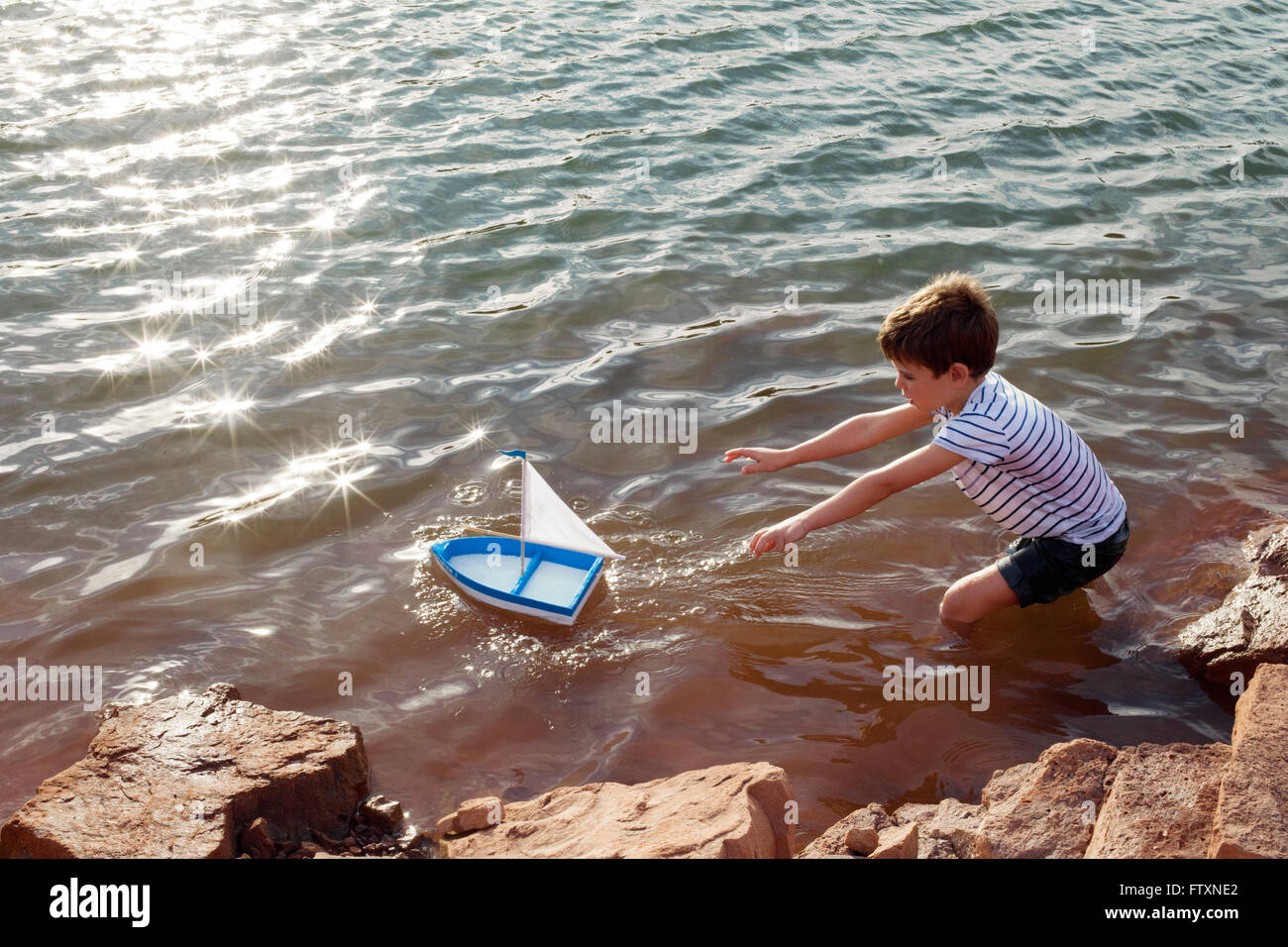 Ragazzo giocando con il giocattolo di barca in un lago Foto Stock