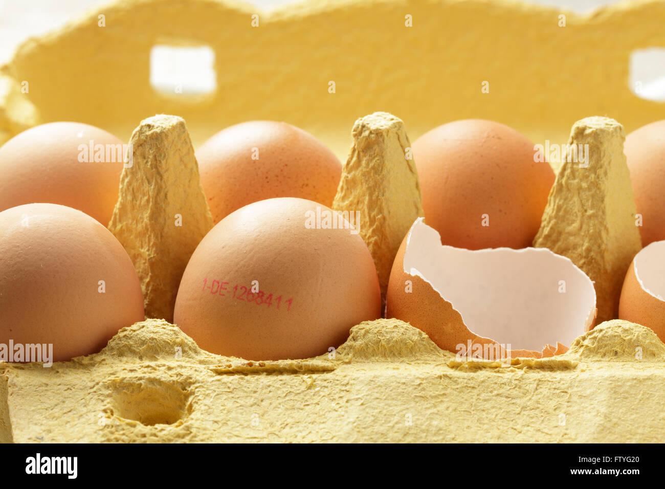 Le uova in una scatola di cartone, alcuni intera alcuni incrinato, Mostra etichetta di identificazione Foto Stock