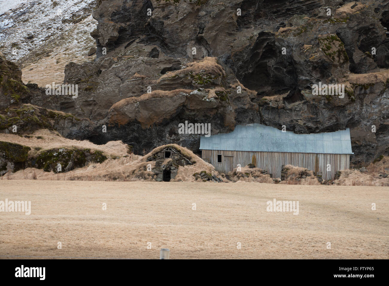Fienile integrato in una parete di roccia in Islanda Foto Stock