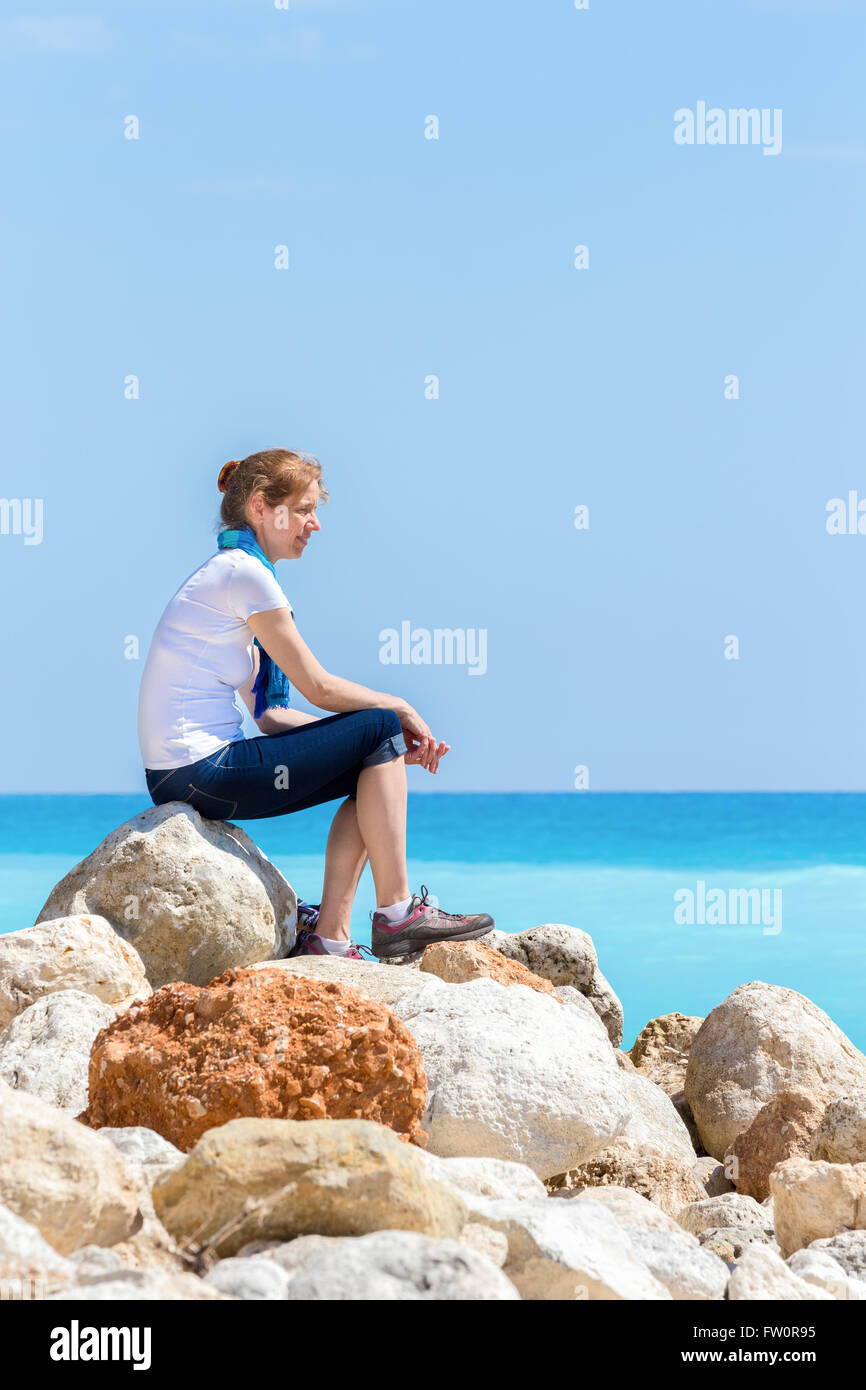 Unione donna seduta sulle rocce a costa vicino al mare Foto Stock