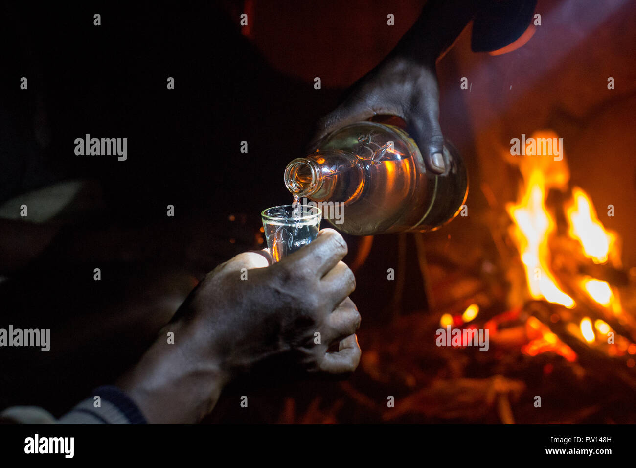 Nord Shewa, Etiopia, 2013: gli agricoltori godetevi un bicchiere di fatti in casa a base di araki attorno a un fuoco. Foto Stock