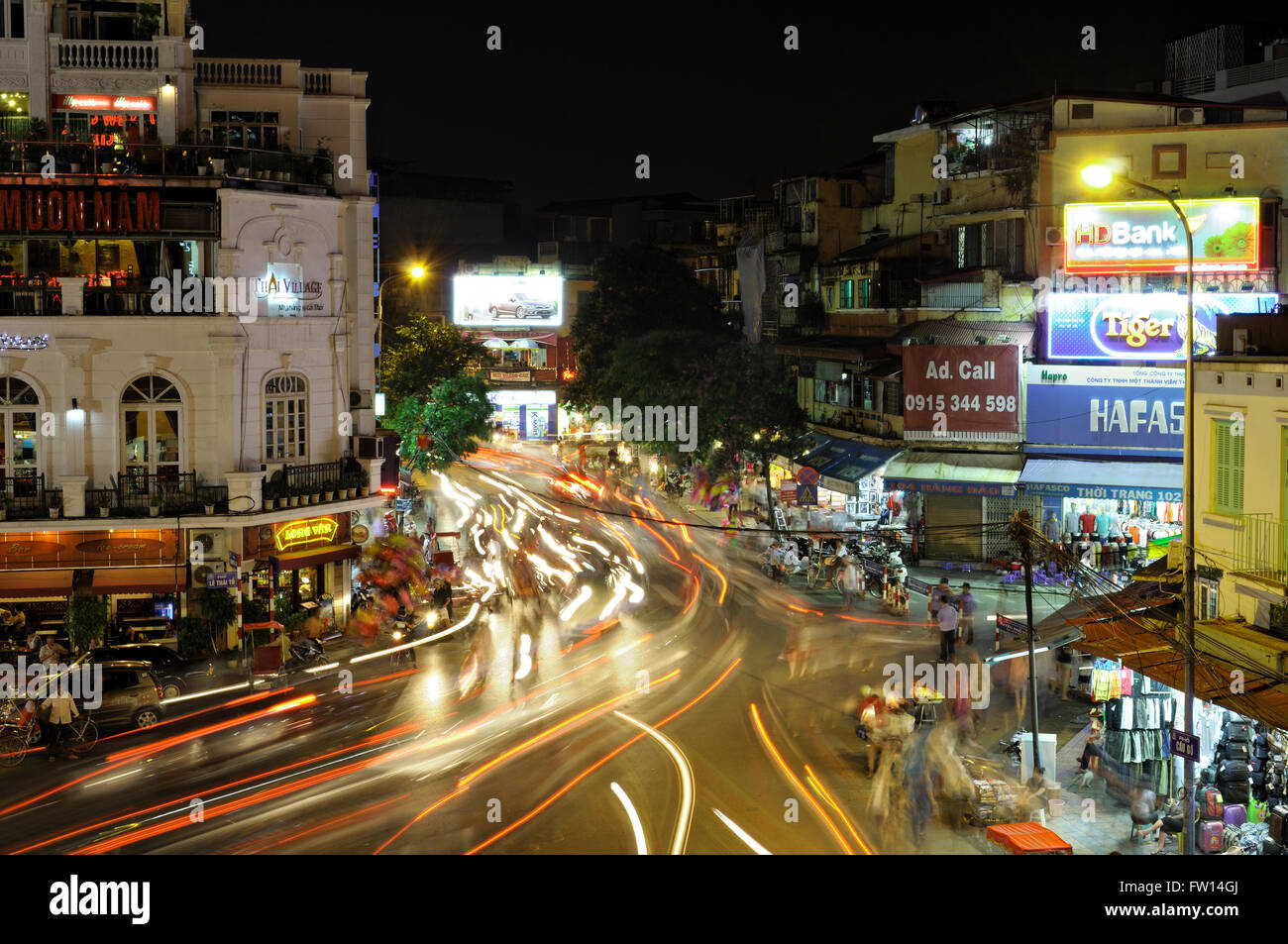 Traffico sentieri di luce da notte a un incrocio occupato nel quartiere vecchio di Hanoi, Vietnam Foto Stock