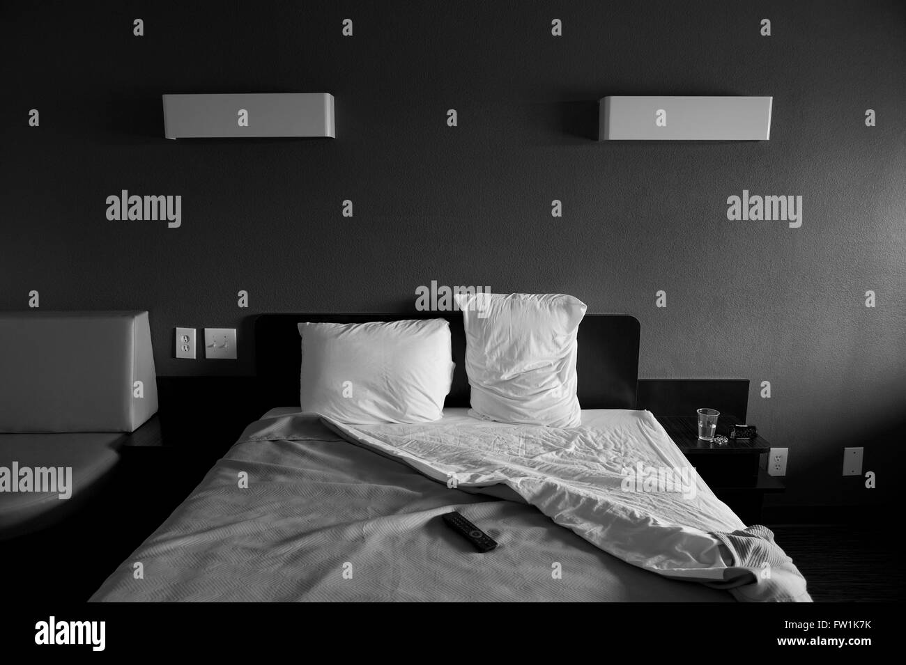 Camera Motel con letto e farmaci bottiglie di pillola sul tavolo laterale con telecomando tv sul letto in bianco e nero Foto Stock