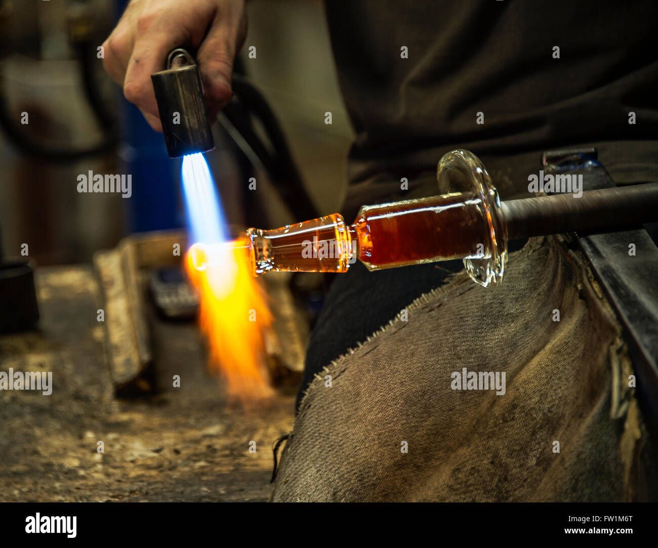 Artigiani di vetro utilizza una torcia a mano per ammorbidire il pezzo egli sta lavorando a. Foto Stock