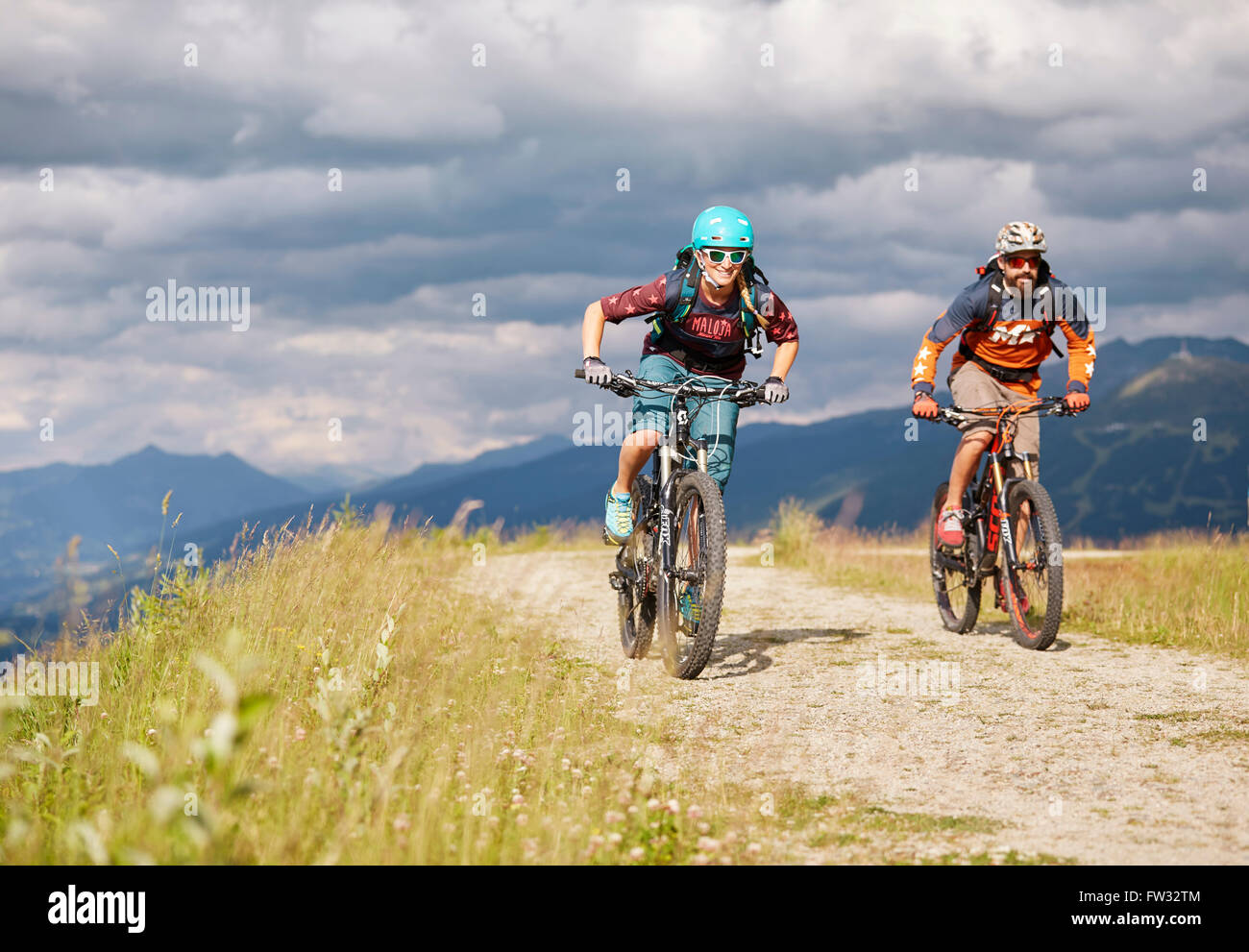 Due mountain bike con i caschi a cavallo su strade di ghiaia, Mutterer Alm vicino a Innsbruck, Patscherkofel, Tirolo, Austria Foto Stock