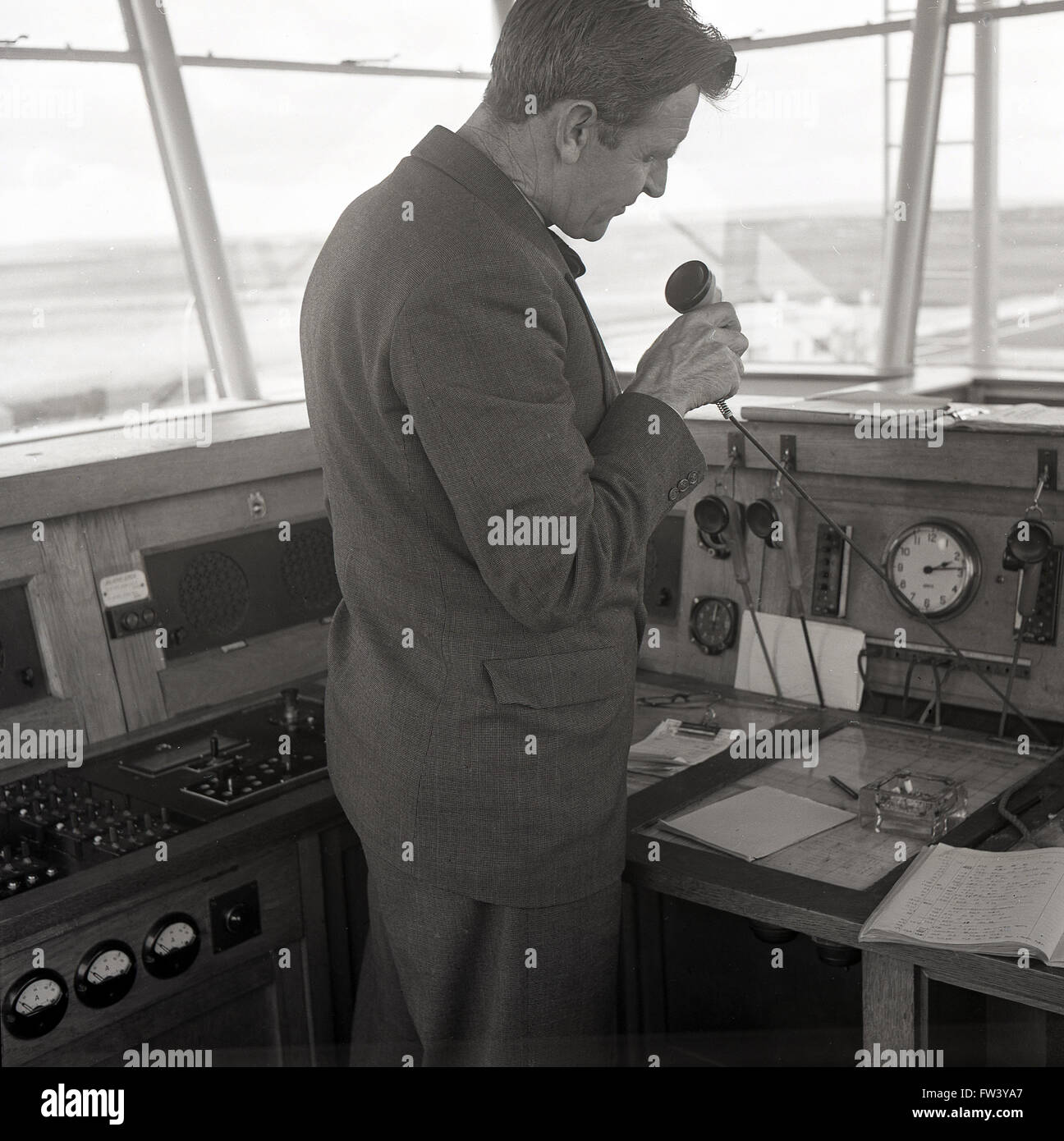 Anni Cinquanta storiche, un traffico aereo ufficiale o operatore nella torre di controllo dell'aeroporto di Dublino, Irlanda parlando in un microfono, Foto Stock