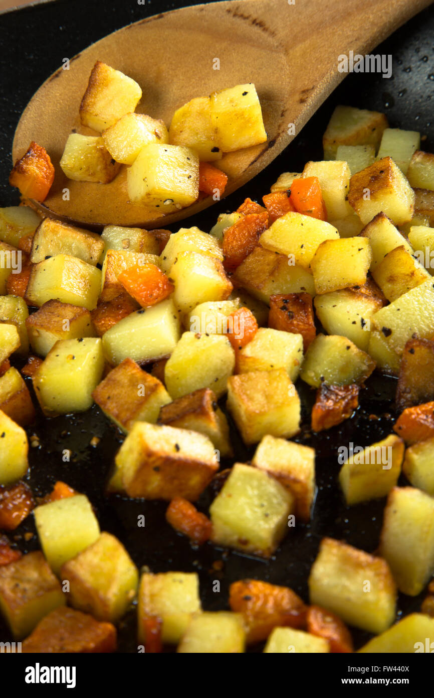 Una macro immagine di verdure a dadini, carote e patate rosolate in una pentola o padella. Foto Stock