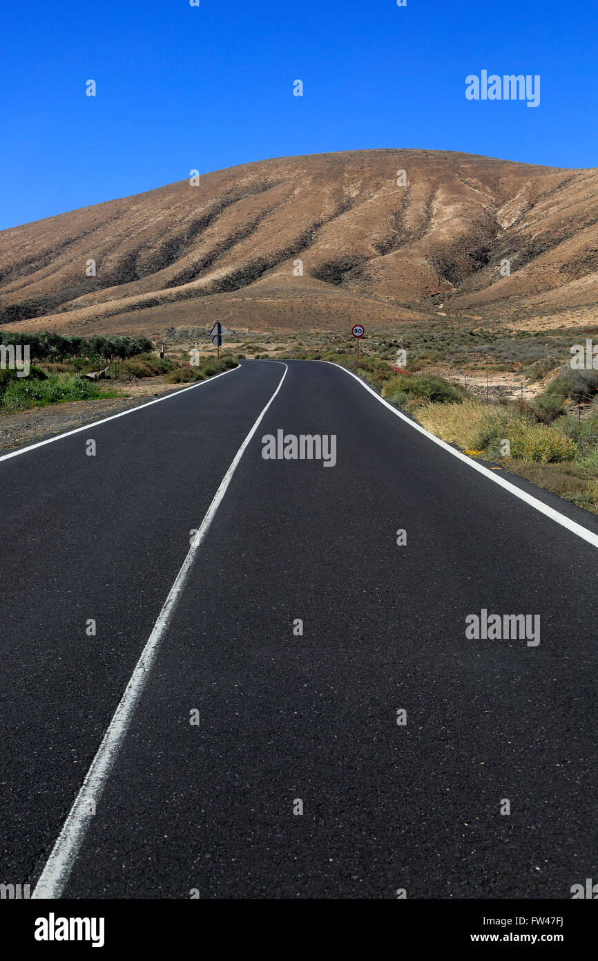 Su strada asfaltata attraversando il deserto, Fuerteventura, vicino a Pajara, Isole Canarie, Spagna Foto Stock