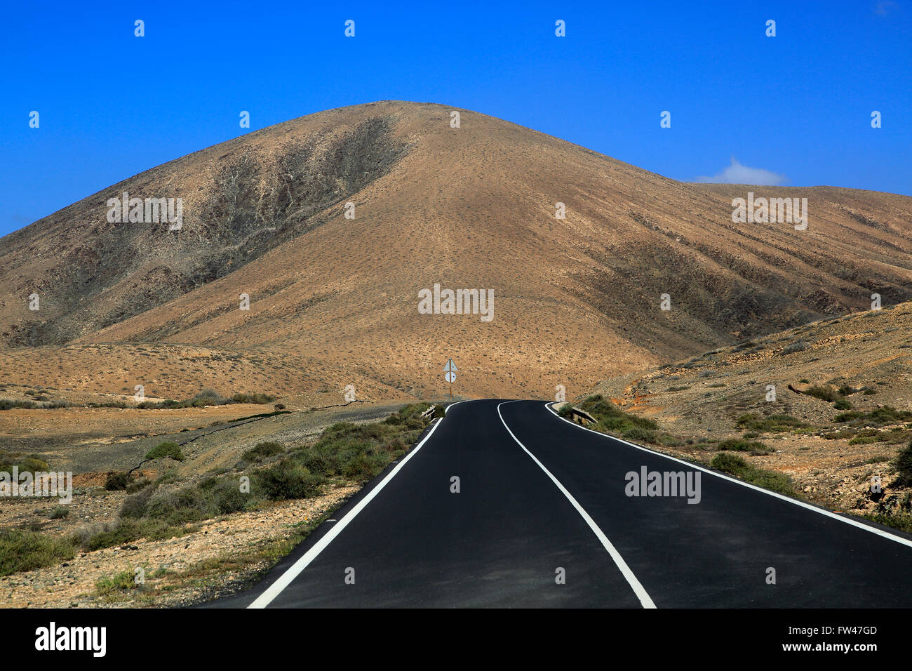 Su strada asfaltata attraversando il deserto, Fuerteventura, vicino a Pajara, Isole Canarie, Spagna Foto Stock