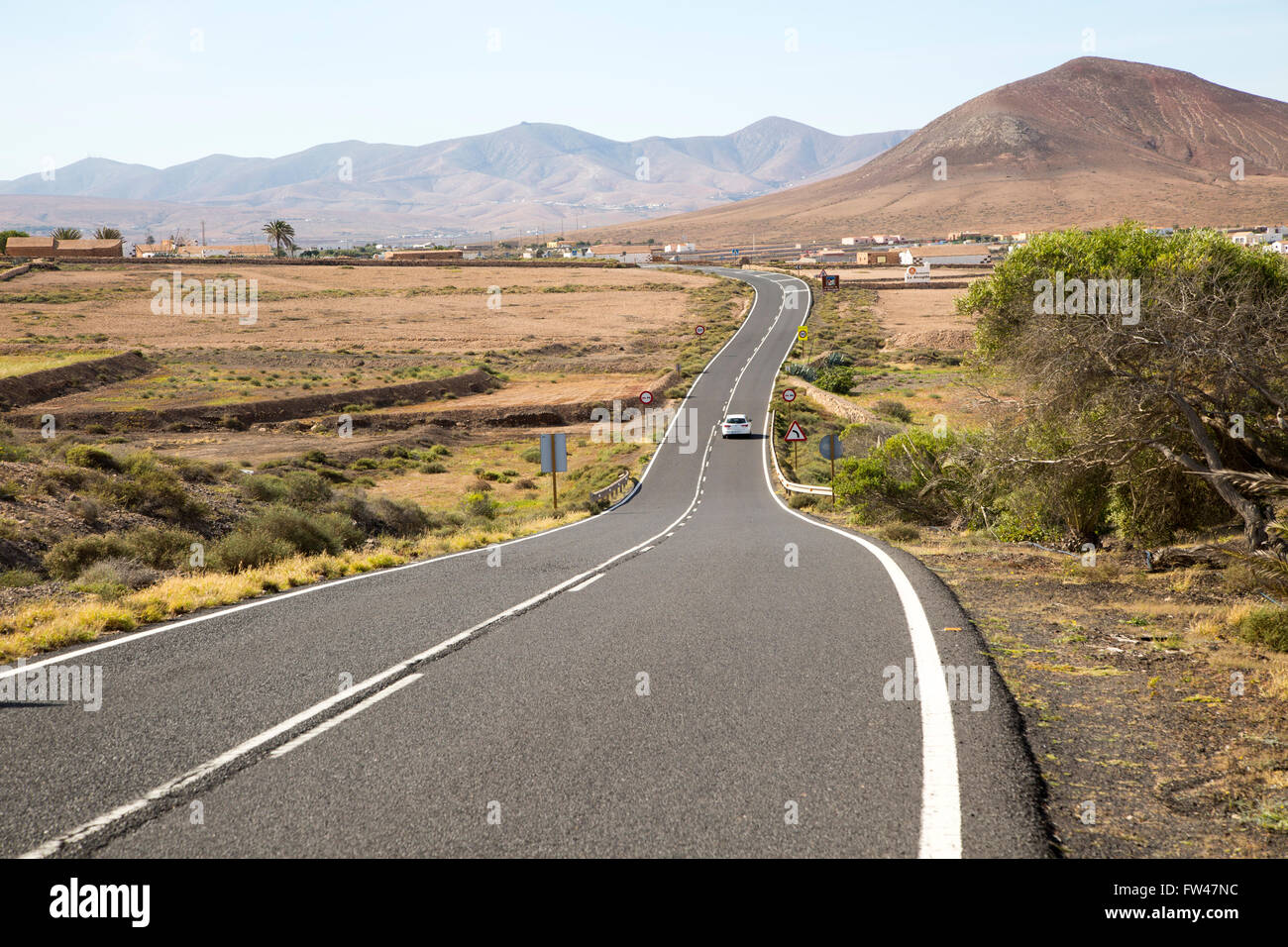 Su strada asfaltata attraversando la campagna, Fuerteventura, Isole Canarie, Spagna Foto Stock