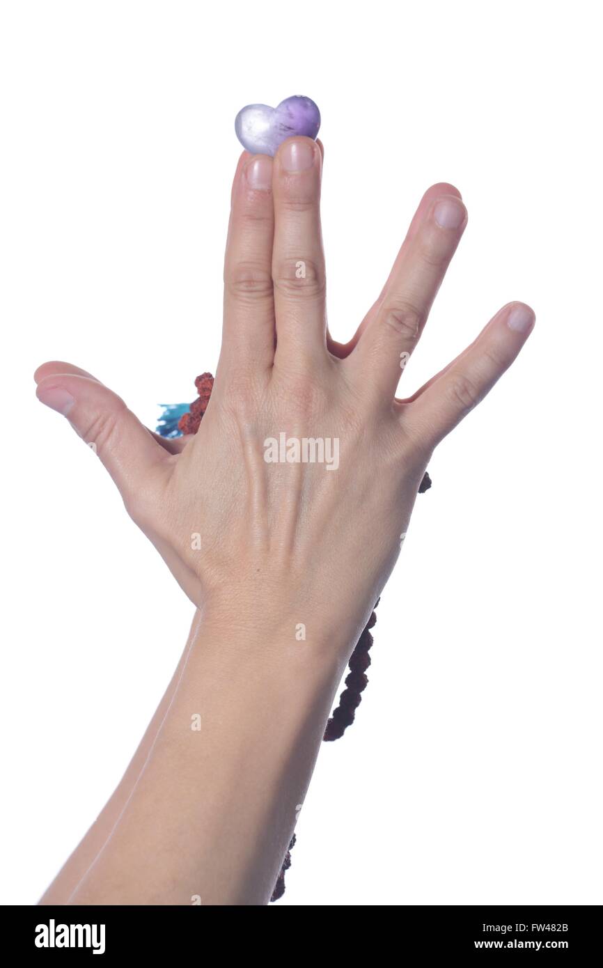 Mano con un cuore fatto di un minerale, su uno sfondo di colore bianco Foto Stock