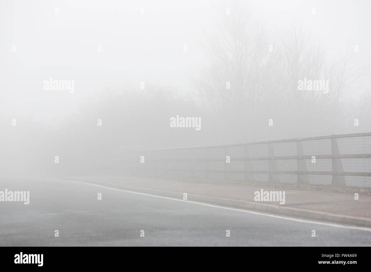 Un ponte su una strada con parapetti disappeaaring nella nebbia. Foto Stock Un ponte su una strada con parapetti disappeaaring nella nebbia. Foto Stock