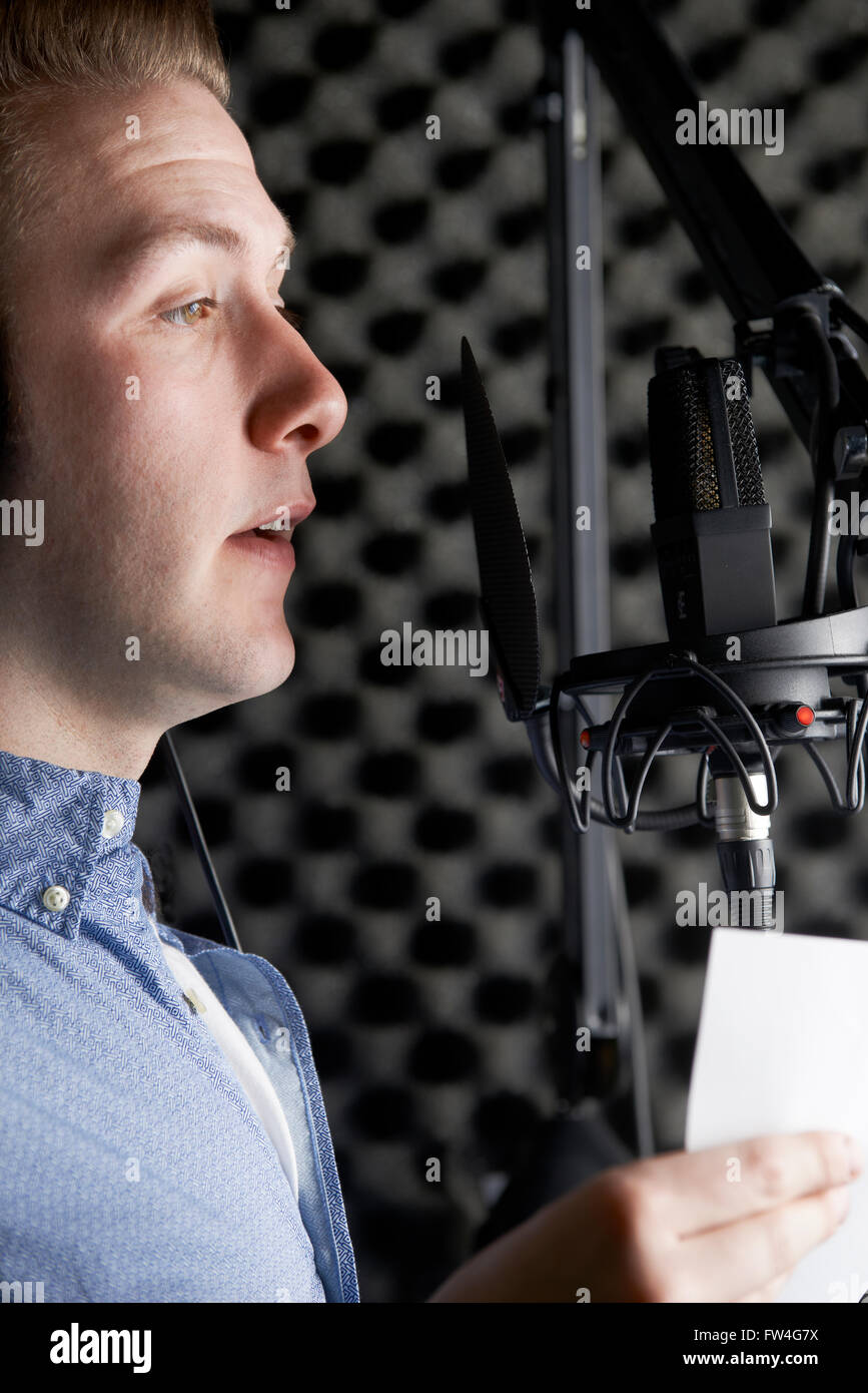 Uomo in studio di registrazione parlando nel microfono Foto Stock