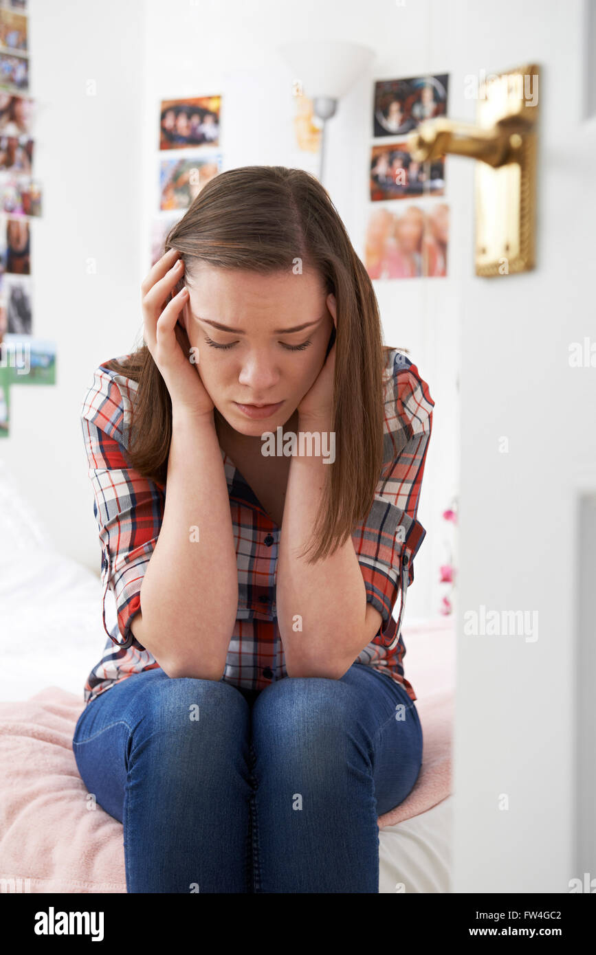 Premuto ragazza adolescente seduto in camera da letto Foto Stock