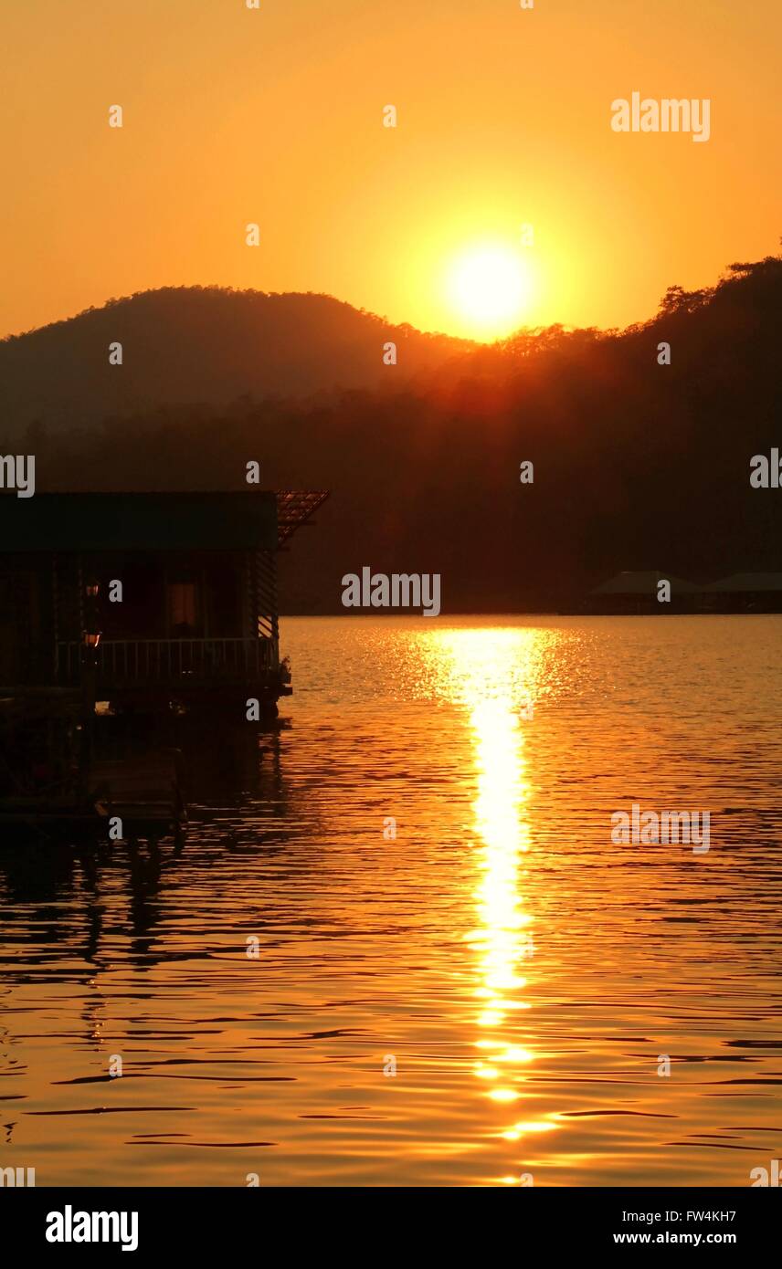 Silhouette di legno casa galleggiante durante il tramonto dorato Foto Stock