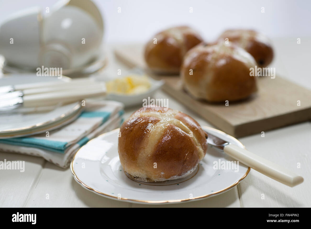 In casa hot cross i panini su una crema verniciato set tavola con raffinati piatti di porcellana cinese e tazze. Foto Stock