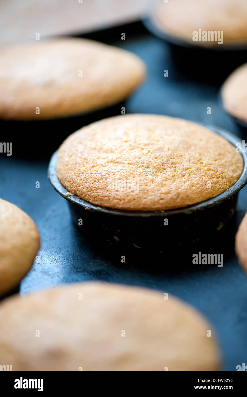 Muffin appena sfornati o tortine in piccole teglie su un vassoio di metallo in corrispondenza di un panificio, vista ravvicinata con il fuoco selettivo Foto Stock