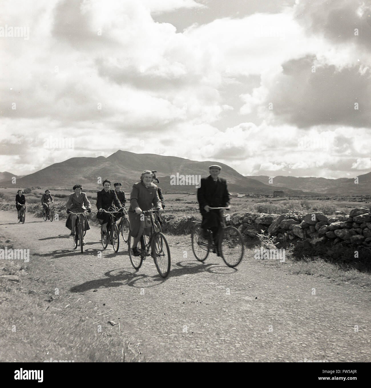 Anni '50, quadro storico di J Allan Cash di alcune persone locali in bicicletta dell'epoca, in bicicletta lungo una corsia rurale in Irlanda occidentale, forse andando a lavorare sulle fattorie e villaggi. Foto Stock