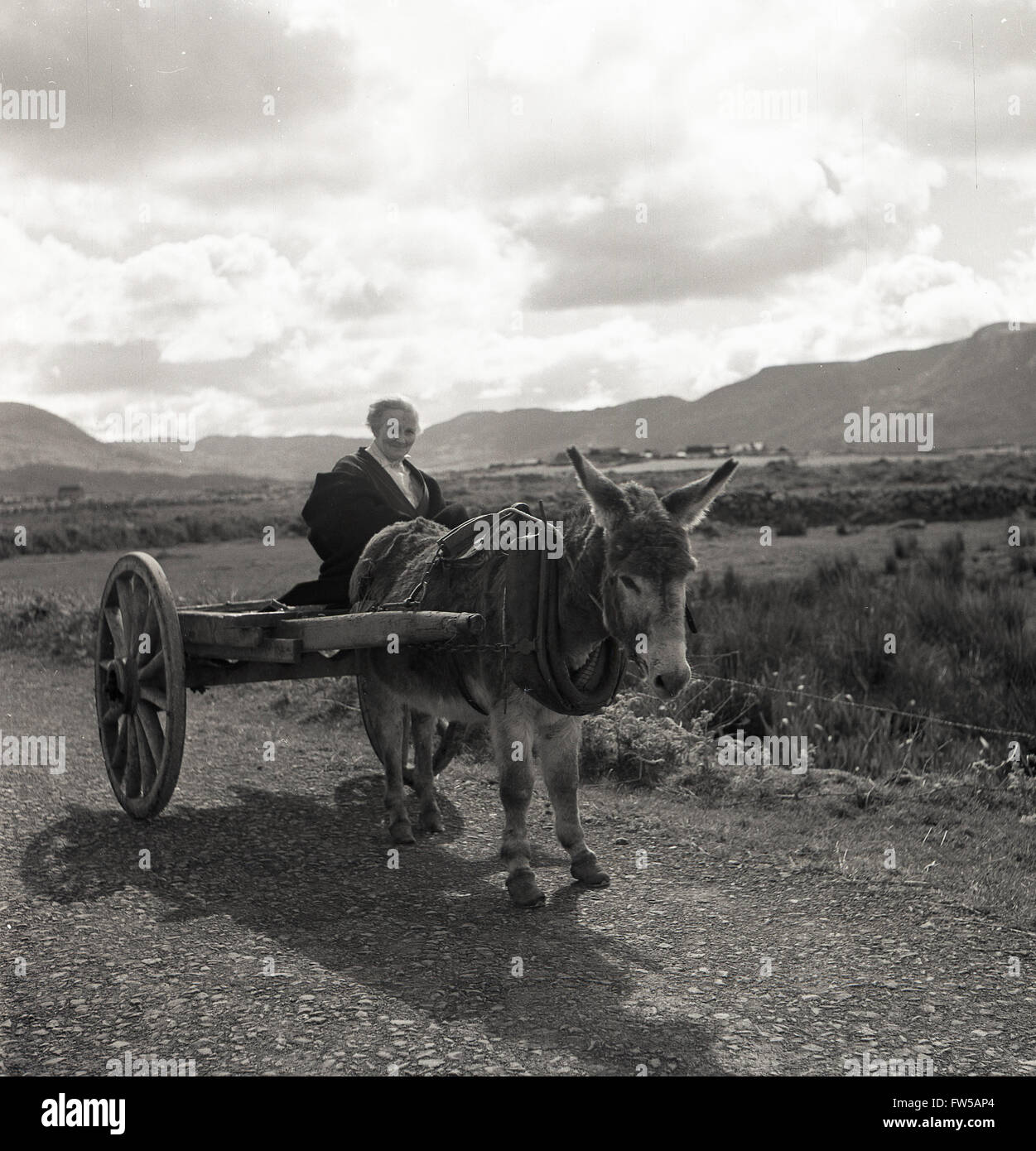 Immagine storica degli anni '50 di J Allan Cash di una donna rurale irlandese su un asino e un carrello su un percorso di campagna in Estremo Ovest dell'Irlanda. Foto Stock