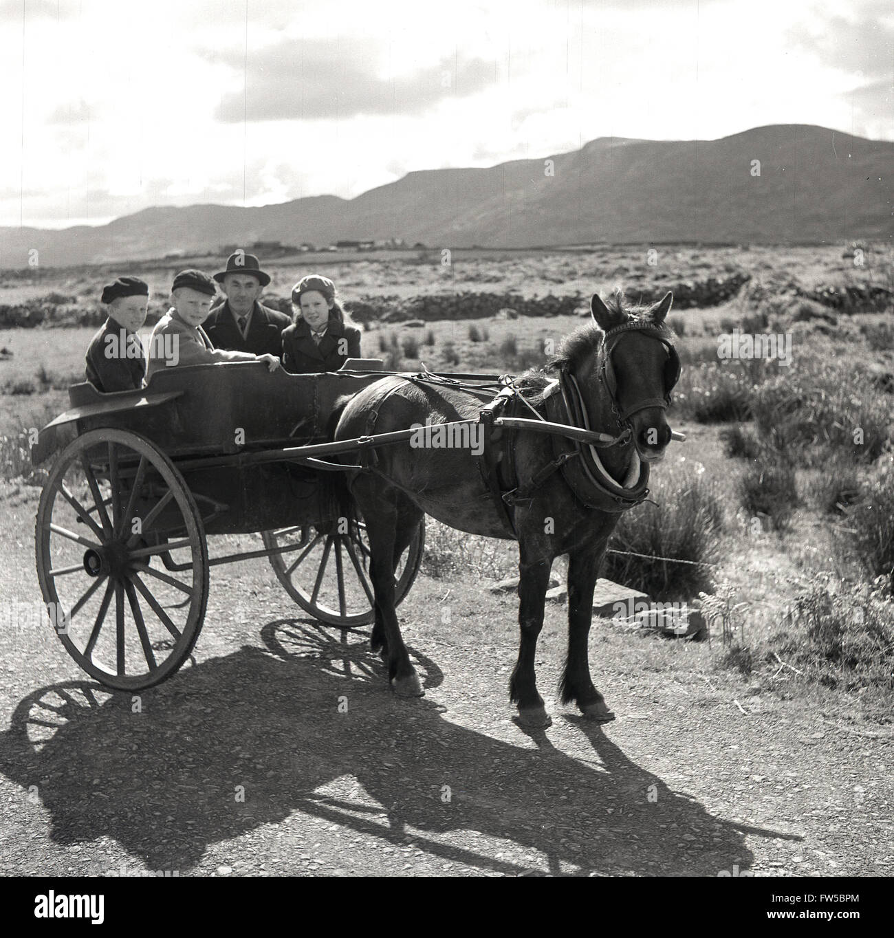Immagine storica degli anni '50 di J Allan Cash di un cavallo e trappola che porta un padre e i suoi tre figli su una corsia rurale nell'Irlanda occidentale. Foto Stock
