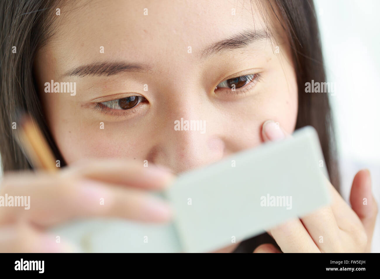 Un costituenti donne asiatiche guardare un piccolo specchio Foto Stock