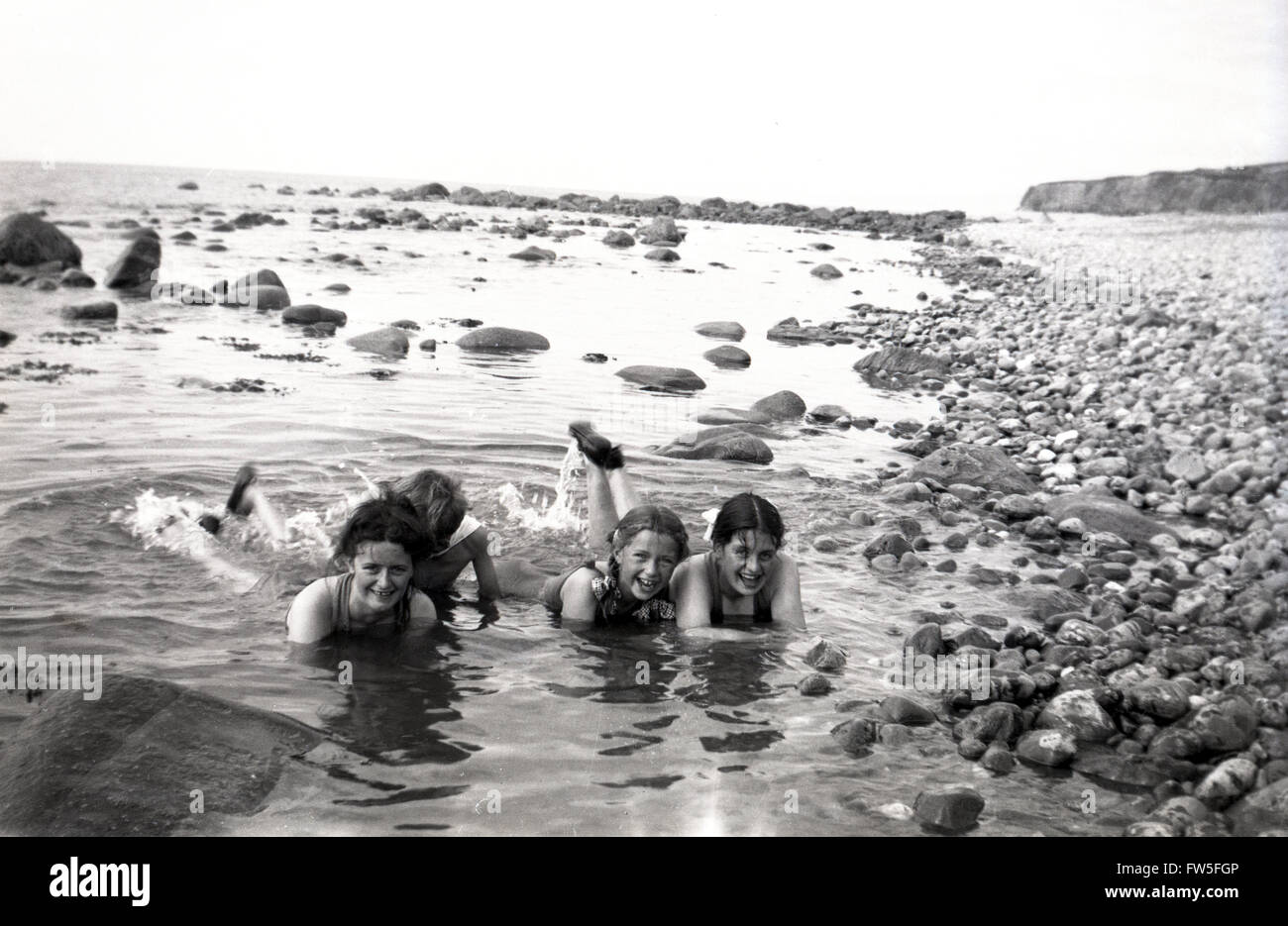 1930s storico, giovani ragazze giacente in piscine di roccia da spiaggia. Foto Stock