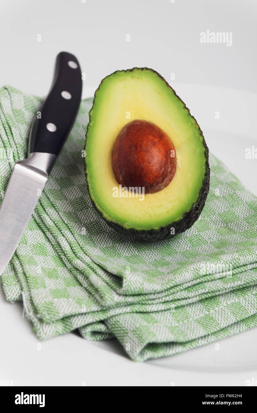 Metà di avocado su asciugamano con coltello Foto Stock