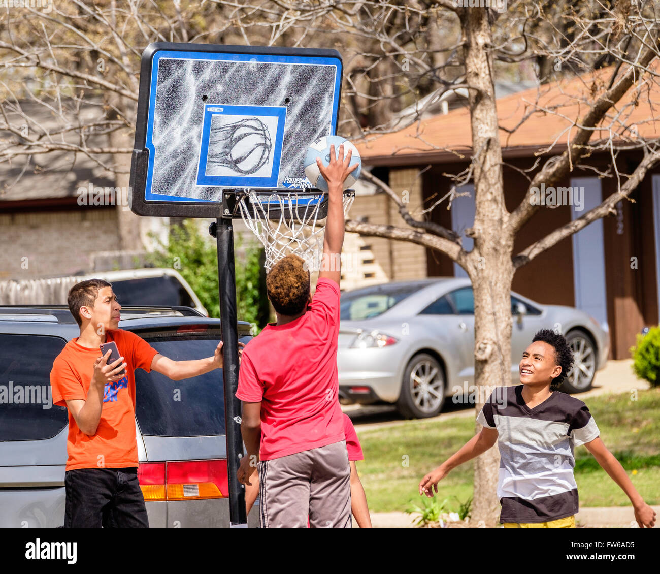 Teen e pre-teen boys raccogliere e giocare a basket su strada nella città di Oklahoma, Oklahoma, Stati Uniti d'America. Foto Stock