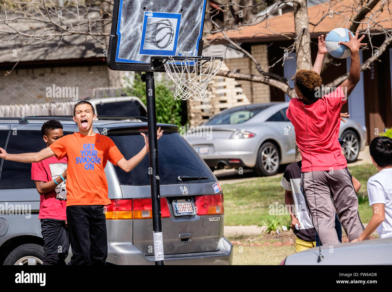Teen e pre-teen boys raccogliere e giocare a basket su strada nella città di Oklahoma, Oklahoma, Stati Uniti d'America. Foto Stock