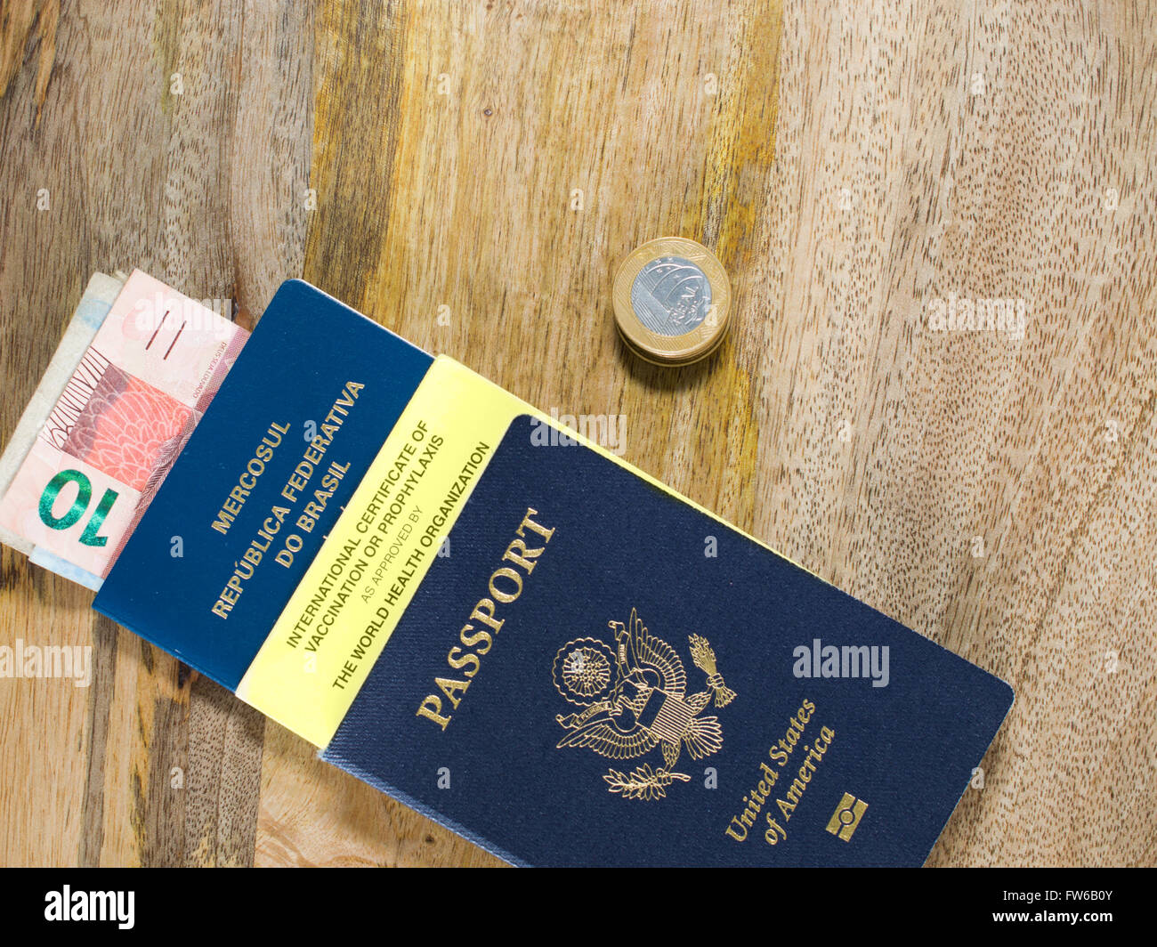Due passaporti, Brasiliano denaro e certificato internazionale di vaccinazione contro di età compresa tra i tavoli in legno. Foto Stock