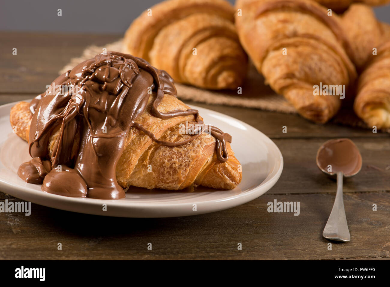 La prima colazione con croissant al cioccolato su un sfondo rustico Foto Stock