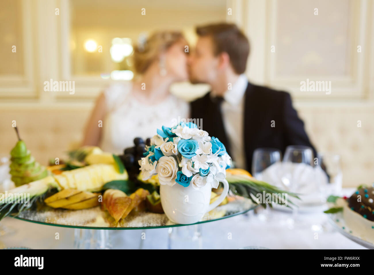 Coppie in viaggio di nozze seduto e baciare a tavola Foto Stock