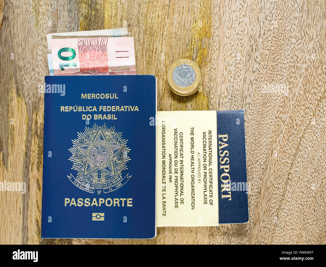 Due passaporti, valuta brasiliana e certificato internazionale di vaccinazione in età compresa tra pannello di legno Foto Stock