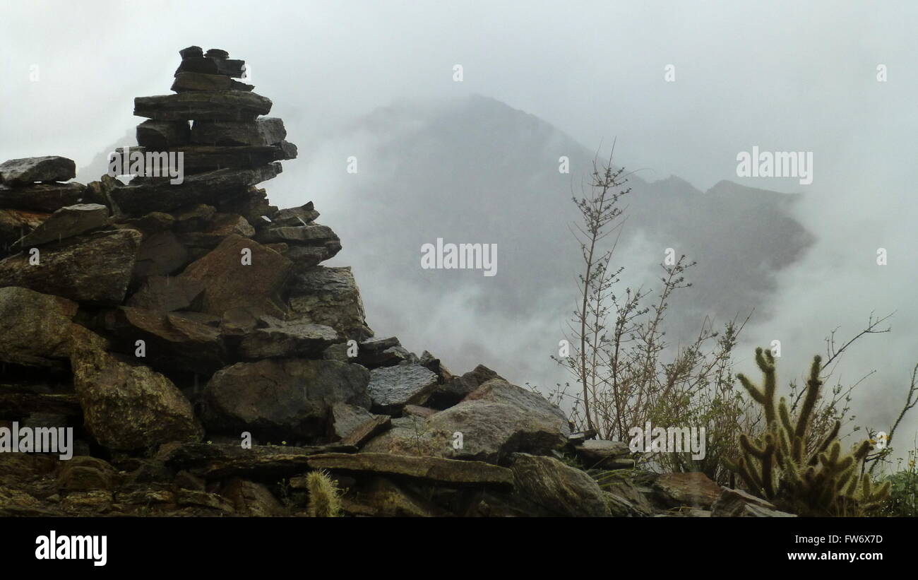 Il tumulo di pietra nel mezzo delle montagne con pioggia e nebbia Foto Stock