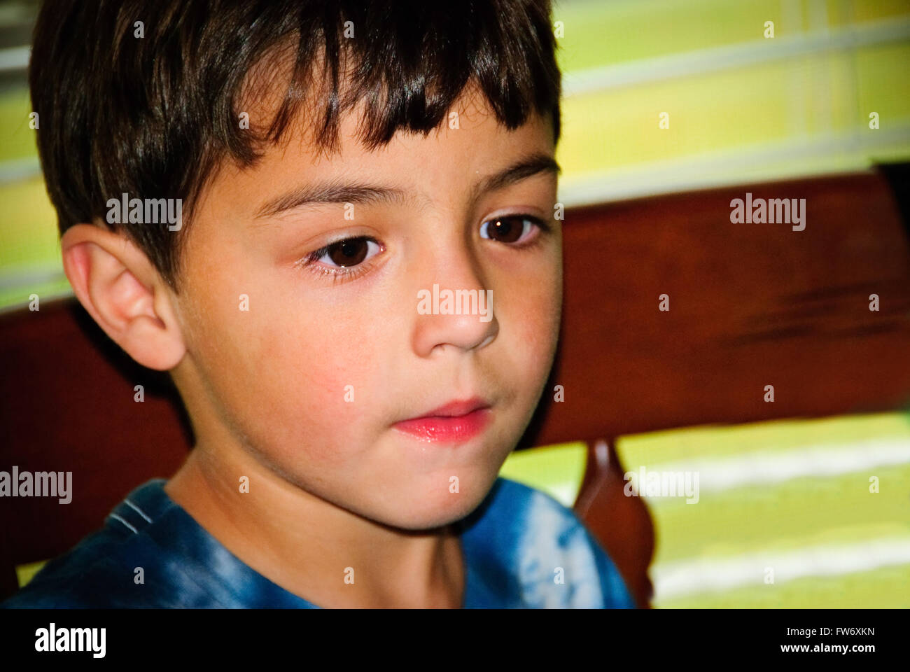 Carino piccolo ragazzo da vicino con i capelli neri e gli occhi marrone scuro cercando gravi. Foto Stock