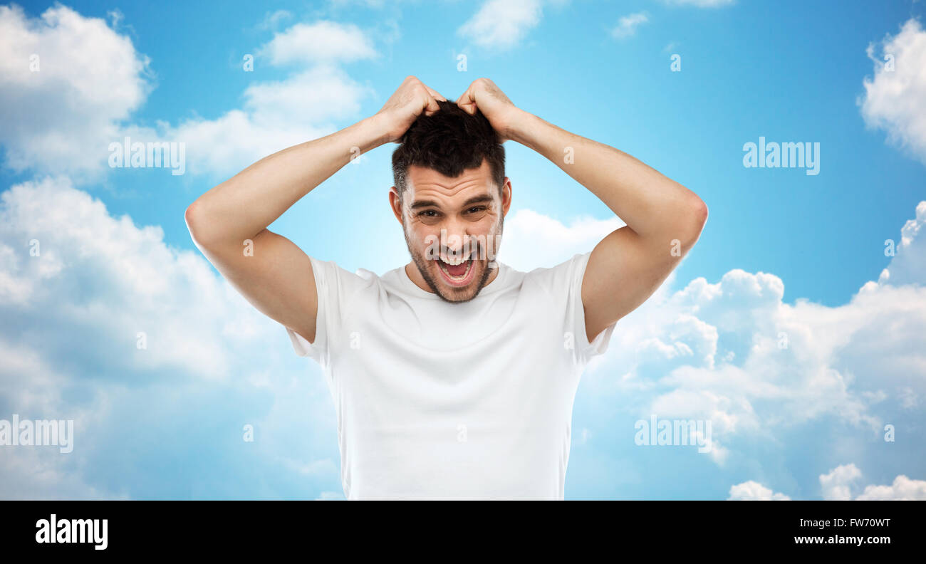 Crazy gridando uomo in t-shirt oltre il cielo blu Foto Stock