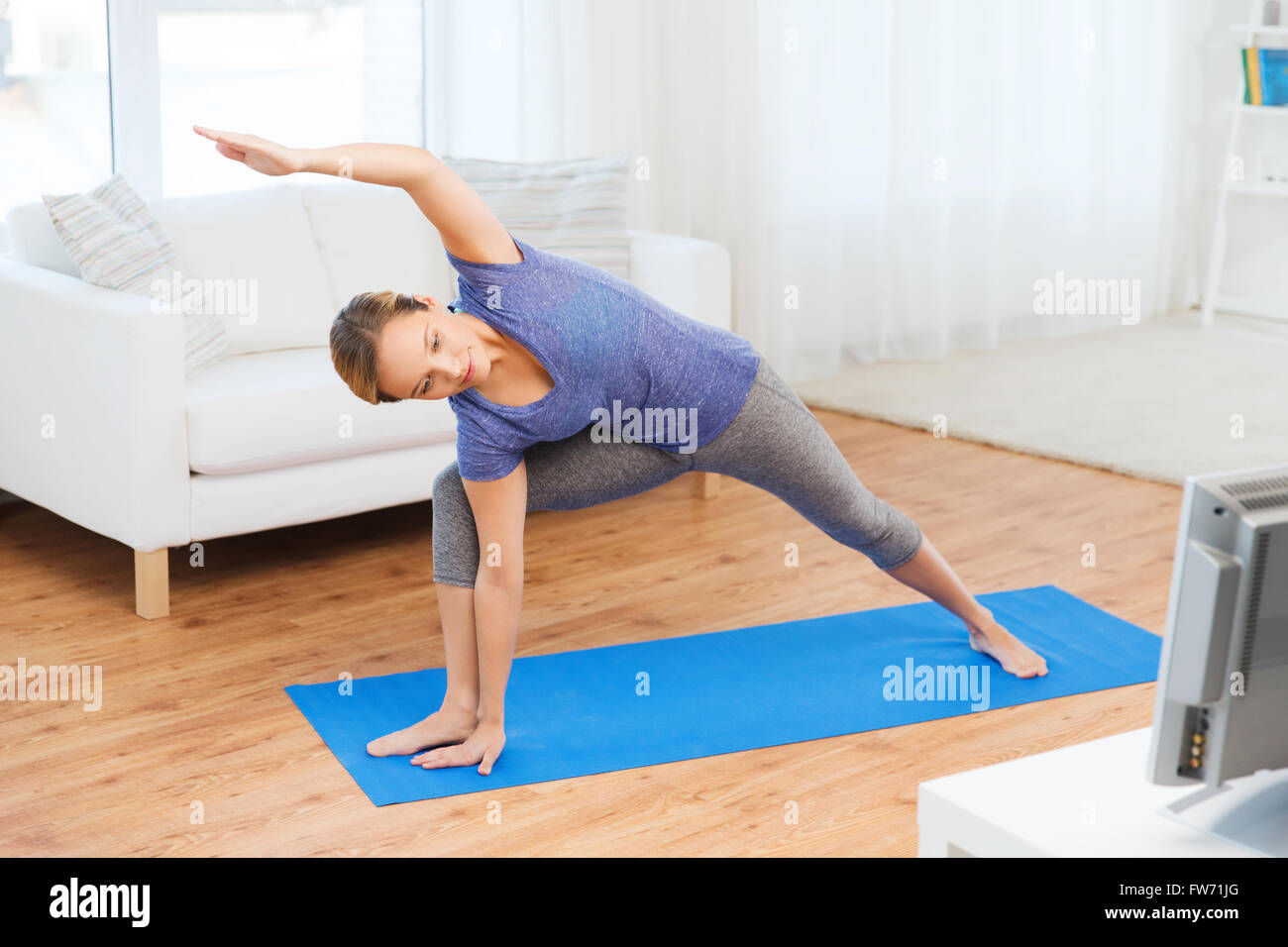 Donna fare yoga bikram triangolo pone sul tappeto Foto Stock