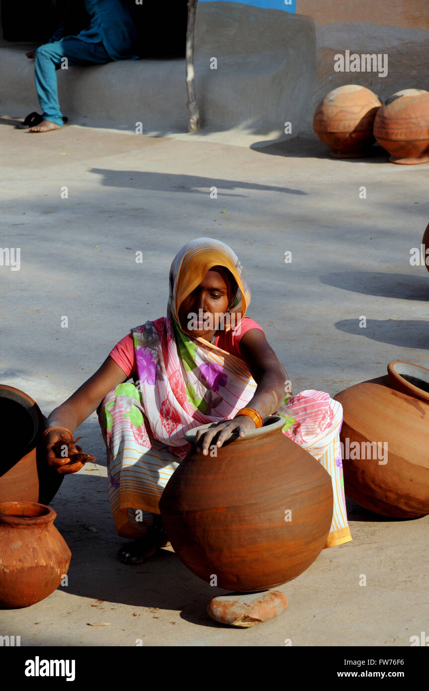 Una donna si applica scivolare al suo pentole in corrispondenza di una ceramica in un piccolo villaggio nei pressi di Khajuraho, Madhya Pradesh in India del Nord. Foto Stock