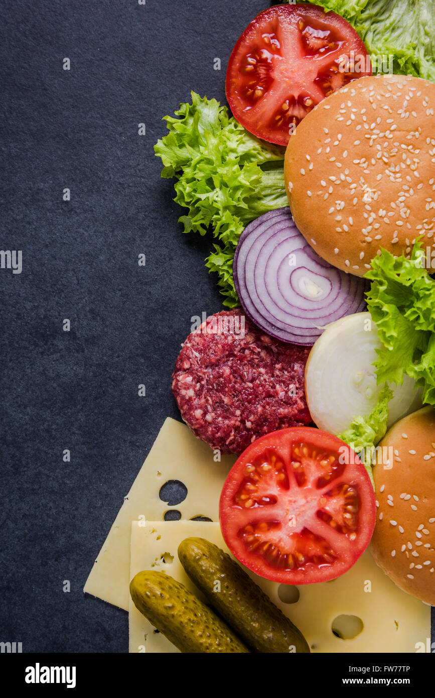 Dark restaurant menu, burger ingredienti e copia dello spazio. In ardesia scura dall'alto. Foto Stock