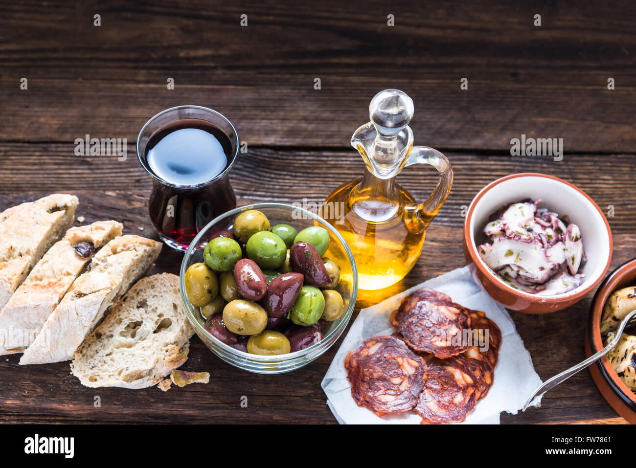Tavola di legno con tapas, olive e salame e olio d'oliva, dal di sopra, copiare lo spazio per testo o annuncio pubblicitario. Foto Stock