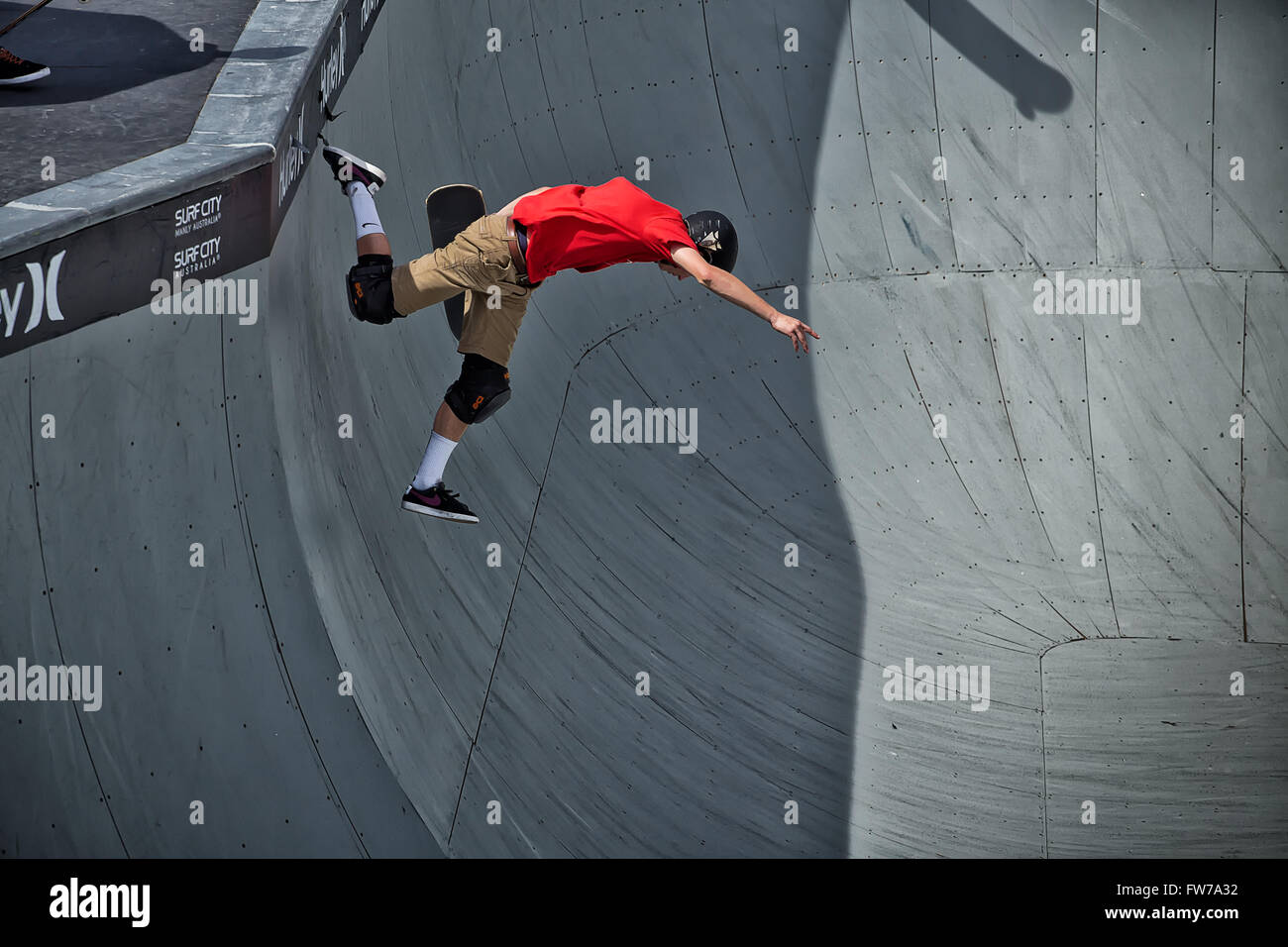 Un lo skateboarder professionista cade attraverso l'aria dalla parte superiore del recipiente in un torneo. Foto Stock