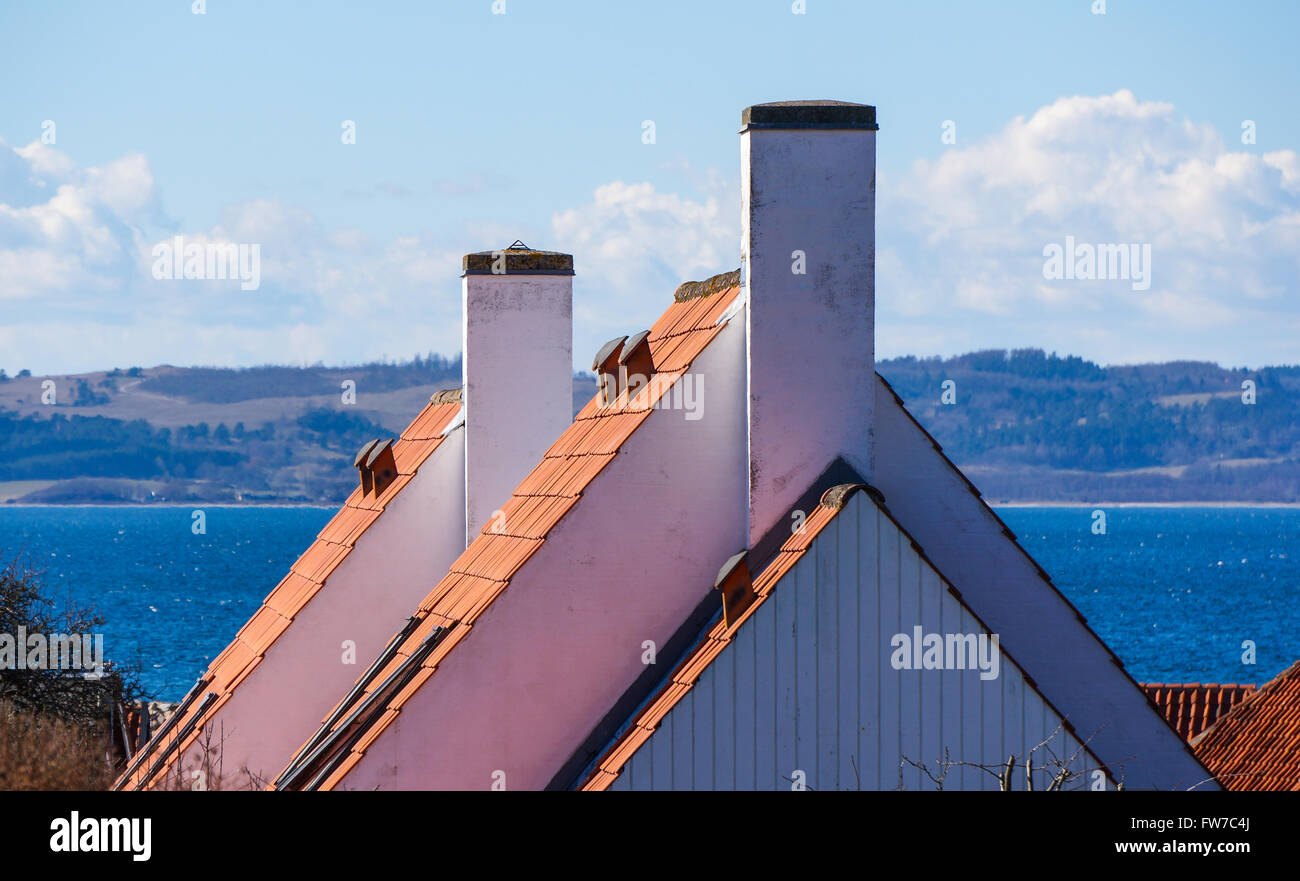 Gables contro il blu del mare, con i camini di bianco e il tetto di tegole. Il campionamento del danese tipico o scandinava di tradizioni edilizie Foto Stock