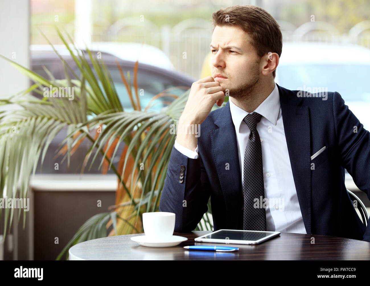 Ritratto di bello uomo di successo bere il caffè e guardare alla tavoletta digitale schermo seduto in coffee shop Foto Stock