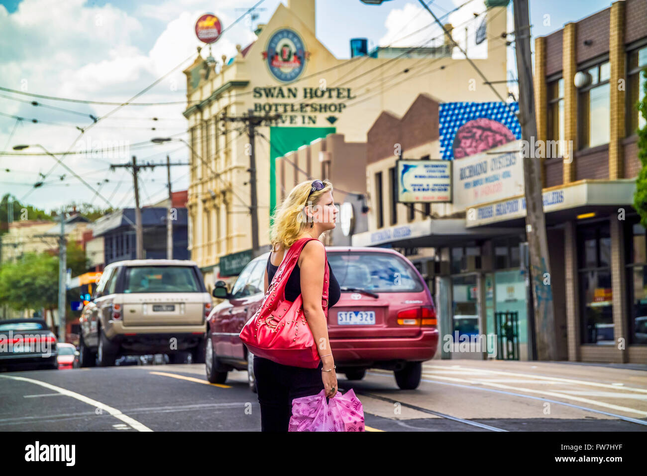 Donna attraversamento strada trafficata, inner city life, Swan Street, Richmond, Melbourne Australia Foto Stock