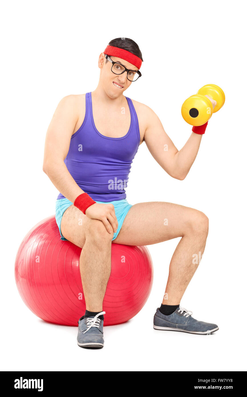 Colpo verticale di un determinato da stupidi guy esercizio con un manubrio seduti su una palla ginnica isolati su sfondo bianco Foto Stock
