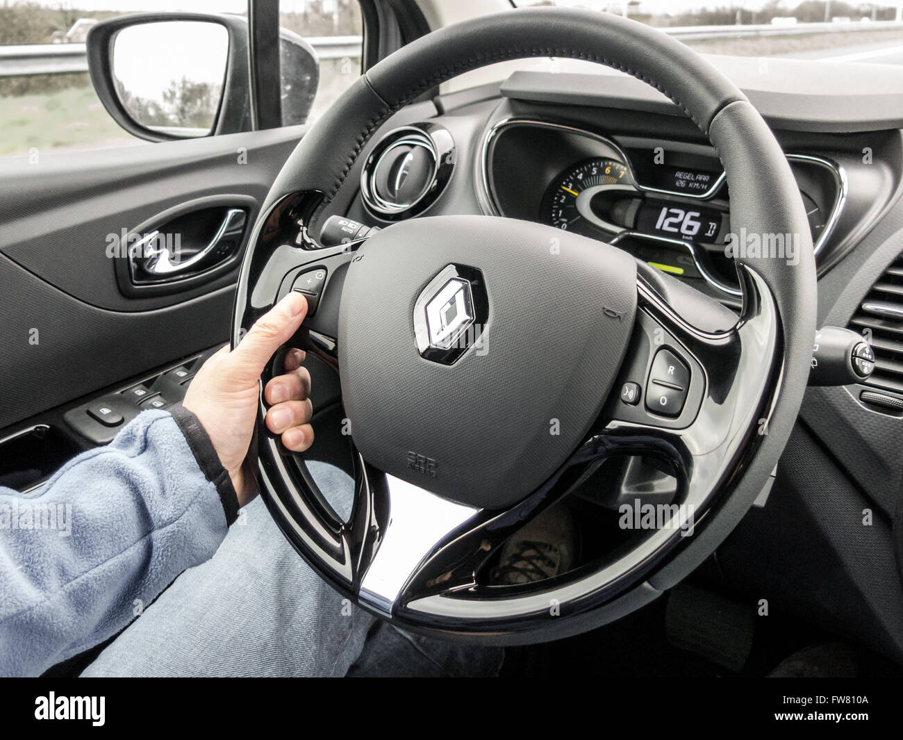Il driver utilizzando il regolatore di velocità al volante durante la guida di un'auto. Gli interni moderni del Renault Captur. Foto Stock