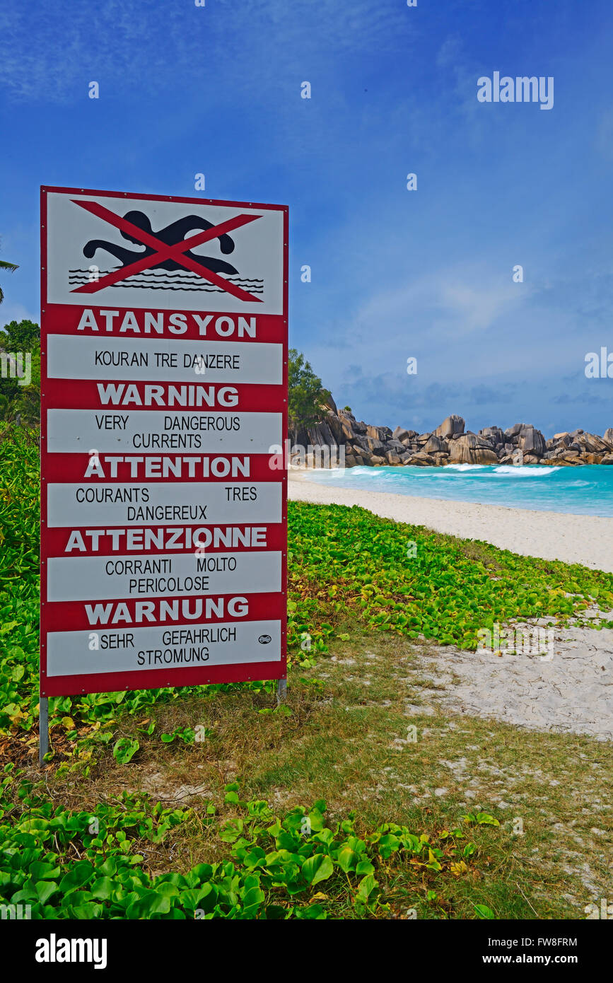 Schild mit Warnhinweisen in unterschiedlichen Sprachen auf Stroemungen, Traumstrand Grand Anse, Insel La Digue, Seychellen Foto Stock